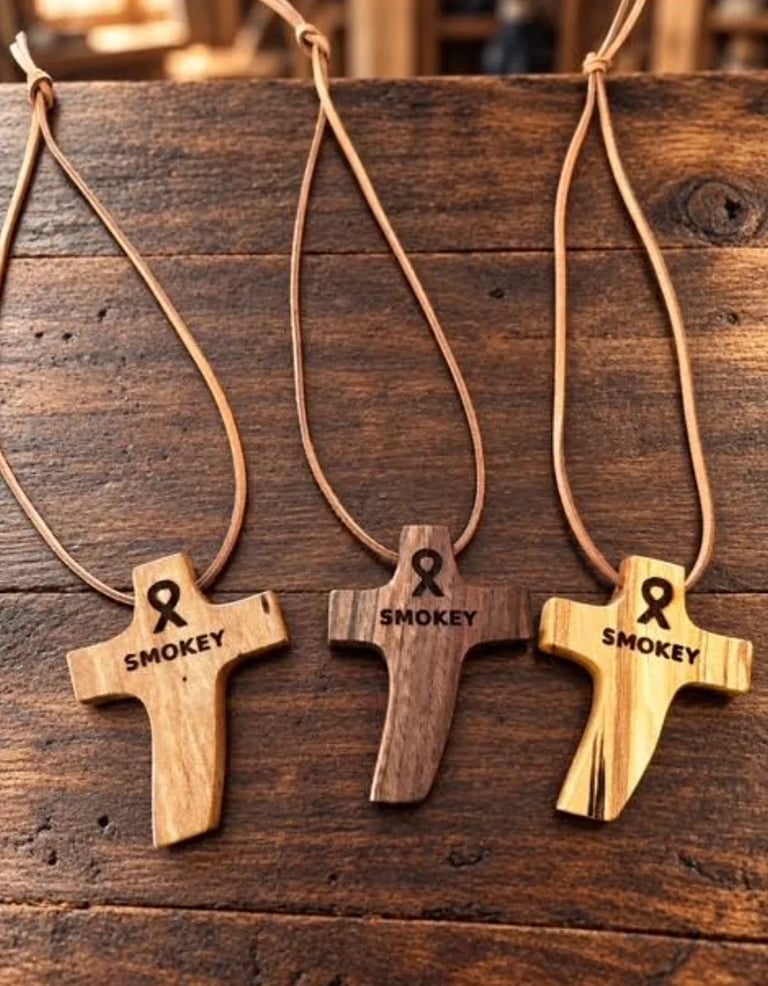 Three wooden cross necklaces with leather cords engraved with Smokey the Bear logo on a rustic wooden surface